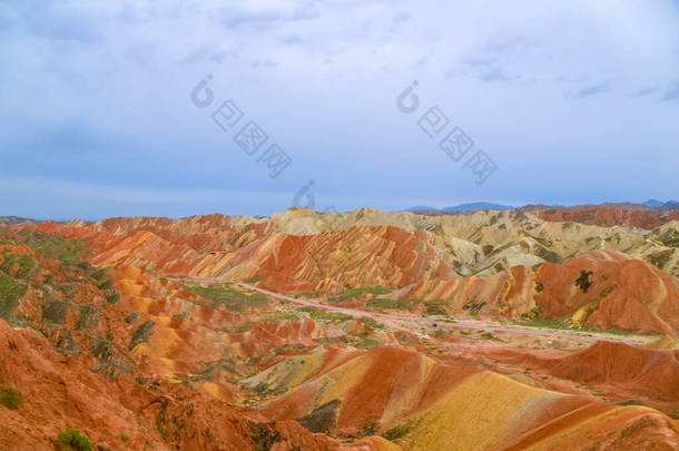 彩虹山迷人的风景和夕阳西下的蓝天背景.中国甘肃张业丹霞国家地质公园。五彩缤纷的风景，彩虹的山丘，不同寻常的彩色岩石，砂岩的侵蚀