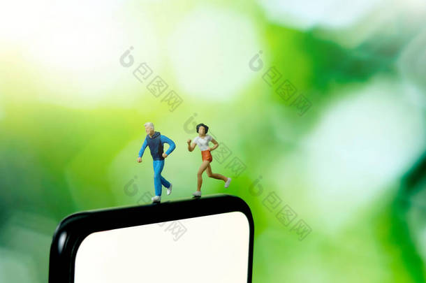 跑步和慢跑跟踪应用程序的概念。一个男人和女人跑过智能手机。微型人物形象摄影.