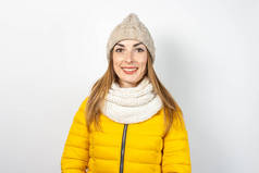 穿着黄色羽绒服、头戴浅色背景帽子的年轻女子。美丽与时尚的概念，冬天，秋天。横幅.