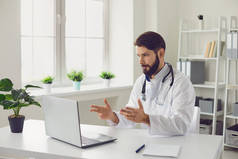 男医生在办公室使用手提电脑，通过视频会议提供医疗咨询.