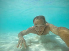 在水下拍下一个没有装备的男子在碧绿的海水中潜水的照片.