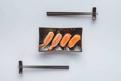 美味寿司与鲑鱼和虾在板上和筷子上的白色分离