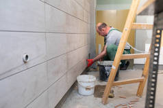 建筑工人小心地把釉料粘在墙上.一个专业的耕作机用粘贴在墙上的方法压住瓷砖.
