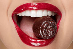 红唇与闪光唇膏和糖果在白色的牙齿