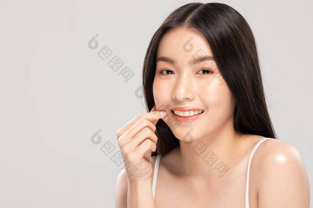 美丽的亚洲女人，用清爽的肌肤<strong>触摸</strong>着柔软的面颊，快乐而快乐，有着积极的情感，有着白色的背景，美感和美感
