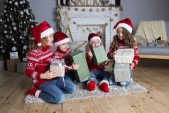 圣诞节快乐，孩子们穿着红色毛衣，在新年前夕打开礼品盒装饰壁炉庆祝圣诞。圣诞节儿童邀请卡。节日问候