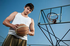 阳光灿烂的日子里，年轻的运动员们在户外打篮球