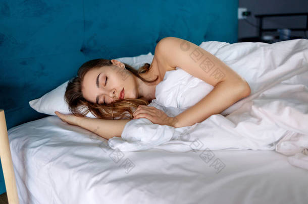 年轻美丽的女人睡在<strong>卧室舒适</strong>的床上.
