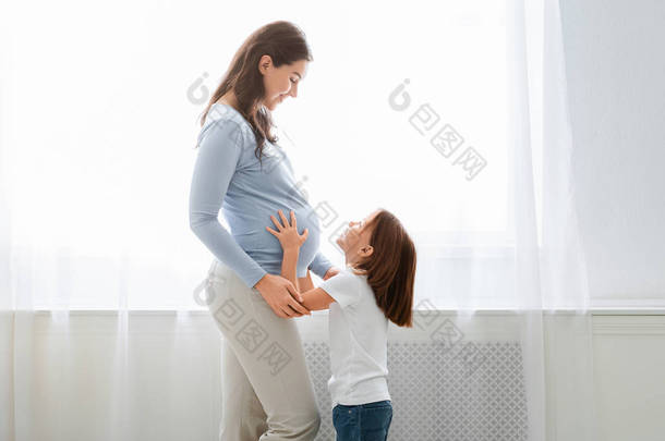 兴奋的小女孩摸着怀孕的妈妈肚子