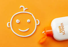 橙色背景的防晒霜。塑料瓶的防晒霜和乳白色的形状,一个微笑的婴儿脸.儿童奶油.
