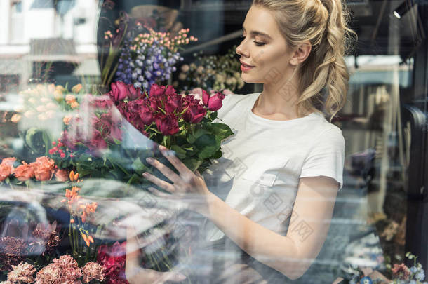 在花店里看有吸引力的花店的橱窗捧着勃艮第玫瑰花