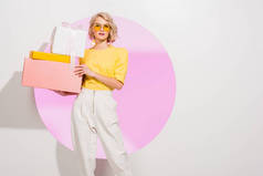 美丽的时尚女孩拿着白色的礼品盒与粉红色的圆圈和复制空间