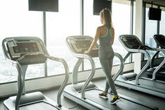 年轻运动的妇女在跑步机在健身房
