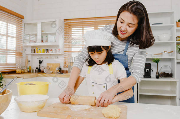 早上，带着学龄前孩子快乐地微笑着的年轻的亚洲日本家庭，在<strong>现代</strong>厨房的家里，吃着烤糕点或派当早餐。做糕点、揉搓面团和烘焙饼干.
