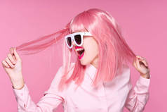 戴着粉色假发和太阳镜的漂亮女人，望着粉红的背景 