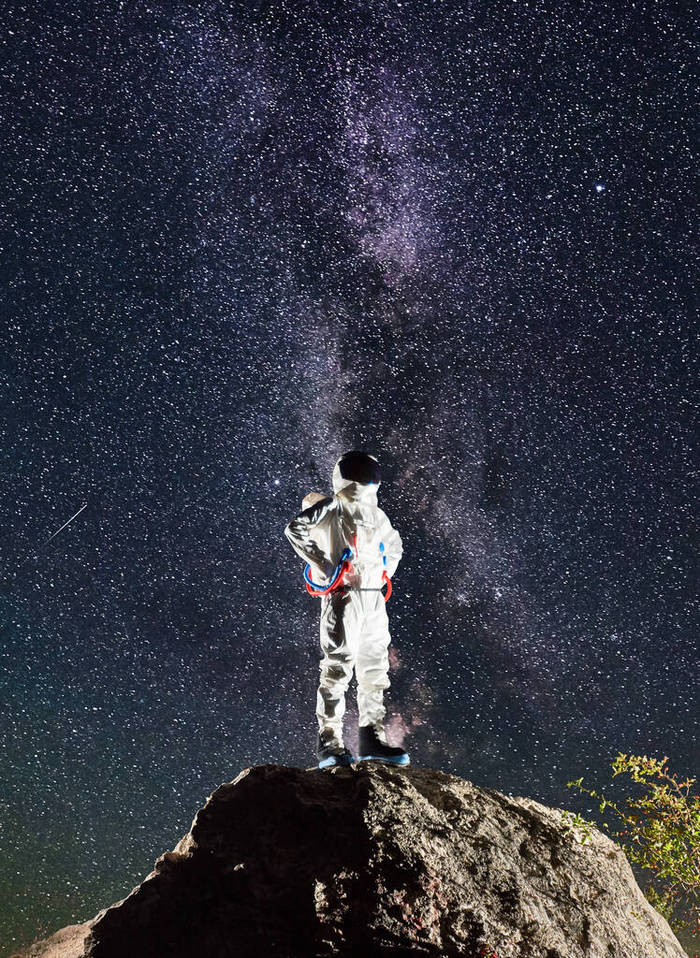 宇航员站在山顶上，背景是星星，迷人的夜空。穿着宇航服的太空人手挽手.宇宙航行、银河道和空间旅行的概念.