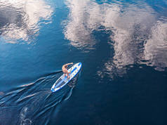 在蓝色的海水上划船的人。 空中俯瞰板