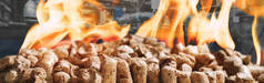 在工业锅炉的背景下，用生物燃料加热工业锅炉房的木制球团。复合混合媒体横幅图像木本生物量在燃烧的火焰背景下的特写。现代能源概念