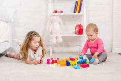 可爱的姐妹在儿童房的地毯上玩建设者