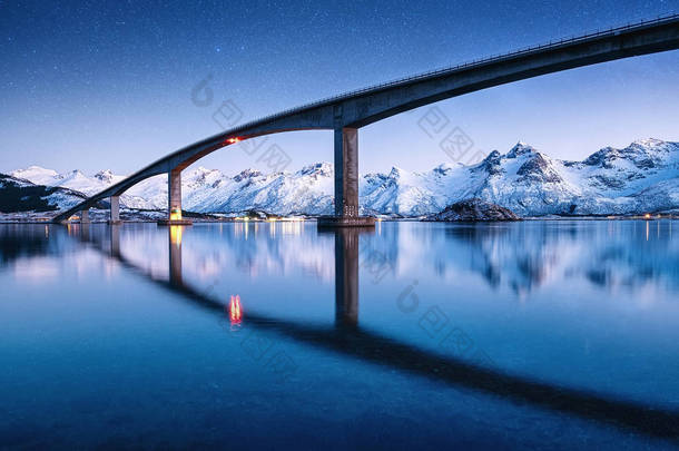 桥、水和夜空都有星星. 水面上的反光。 挪威的自然景观在夜间。 旅行-形象