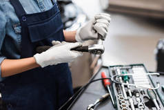 机修工手手握手套在车库工具箱附近修理设备的近景