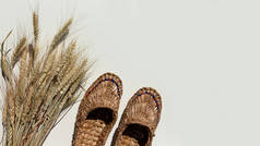 一双旧的帆布鞋和一束浅色背景的小麦。复制空间.