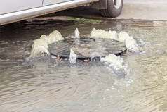 事故排水系统。 水从下水道流过马路. 水从下水道流过马路. 下水道的事故.