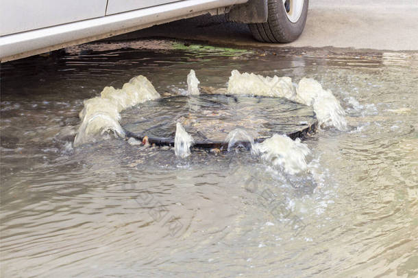 事故排水系统。 水从下水道流过马路. 水从下水道流过马路. 下水道的事故.