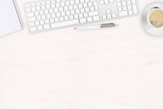 白色木制办公桌顶部视图, 带电脑键盘、记事本、钢笔和带复印空间的咖啡杯