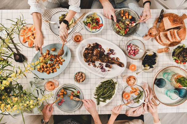 家人，<strong>朋友</strong>聚餐平躺的人手在桌子上烤羊肩，沙拉，蔬菜，小吃，玫瑰酒和米莫萨树枝，顶视图。庆祝<strong>派对</strong>晚宴