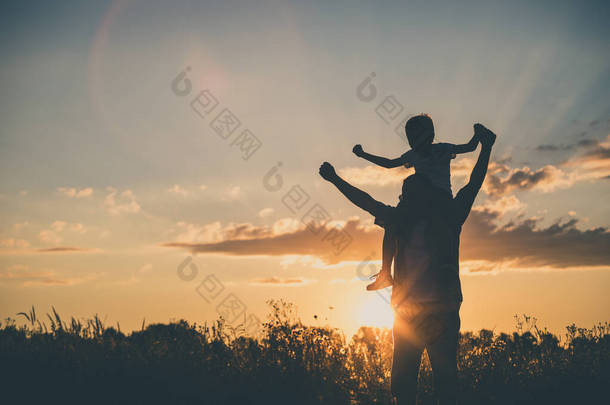 父亲和儿子在日落的时候在公园里玩。人们在开心的在球场上。友好的家庭的概念和的暑假.