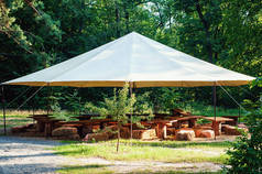 帐篷下的夏季公园里有木制桌子和椅子的咖啡店