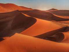 在纳米比亚纳米布沙漠红色沙丘的曲线、线条和阴影上升起的太阳.