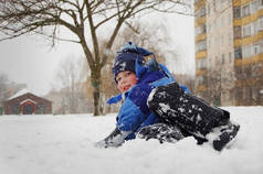 这个男孩在冬天躺在雪地上玩雪.他喜欢这样的天气和孩子们在雪地里的游戏
