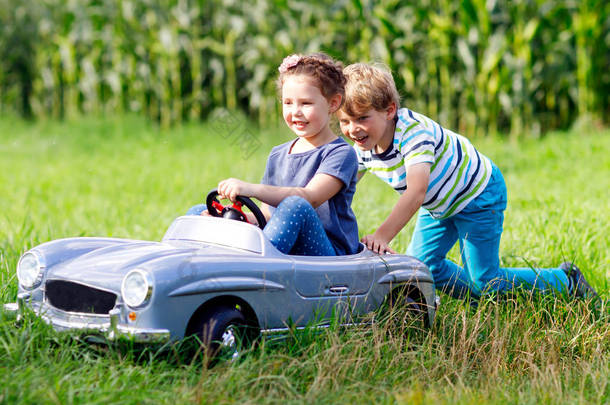 两个<strong>快乐的孩子们</strong>玩在夏天<strong>的</strong>花园里，室外大旧玩具车