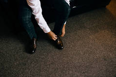 一个优雅的男人穿黑色, 皮革, 正式的鞋。系鞋带