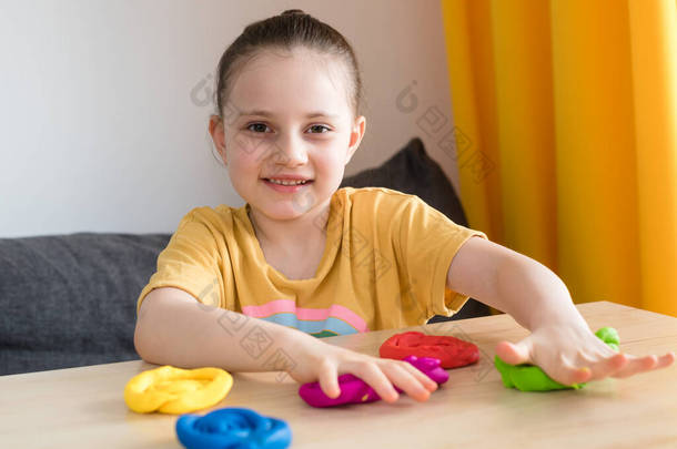 孩子在玩彩色黏土.自制的塑料线。为被隔离儿童开展的活动。女孩在家中被隔离时从塑料中雕刻出来。2021年验尸官.