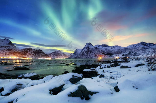 罗弗敦群岛上的北极极光, 挪威。山上的绿色北极光。夜空中的极地灯光。夜间冬季景观与极光和倒影在水面上。自然背景在挪威