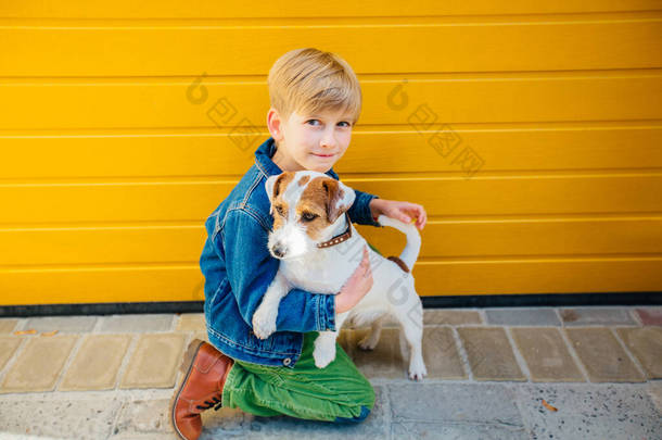 十几岁的男孩在户外和隐藏的狗杰克 · 罗素 · 泰里尔一起玩和聊天。 友谊关系的概念。 狗只保护主人.