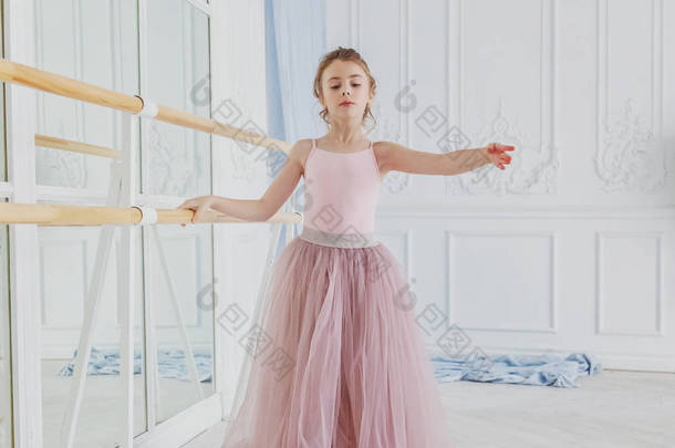 舞蹈课上年轻的古典<strong>芭蕾舞女</strong>.美丽优雅的<strong>芭蕾</strong>舞演员在白色灯堂的大镜子前练习穿着粉色短裙的<strong>芭蕾</strong>舞姿势