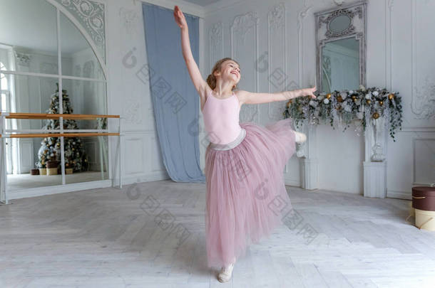 舞蹈课上年轻的古典芭蕾舞女.美丽优雅的芭蕾舞演员在白色灯堂的大镜子前练习穿着粉色短裙的芭蕾舞姿势