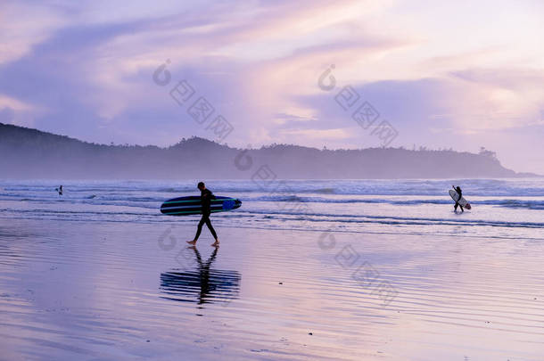 温哥华岛太平洋沿岸的冲浪者，在日落时分与船上冲浪的冲浪者，加拿大温哥华岛的冲浪者. 