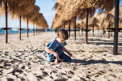 一个小女孩在沙滩上户外的稻草遮阳伞中玩耍.