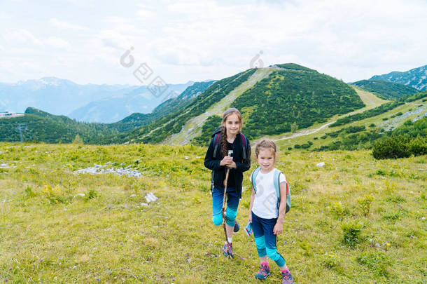 在美丽的夏日里，孩子们在奥地利的阿尔卑斯山中徒步旅行，休息在岩石之上，欣赏高山的壮丽景色。与孩子一起积极<strong>享</strong>受家庭假期。户外<strong>运动快乐</strong>健康.