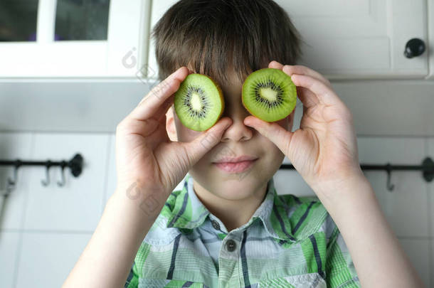 小孩，8-10岁的小孩，坐在厨房里的小孩，多汁的切青猕猴桃<strong>而不是</strong>眼睛，近距离观察，小孩的饮食观念，健康的食物  