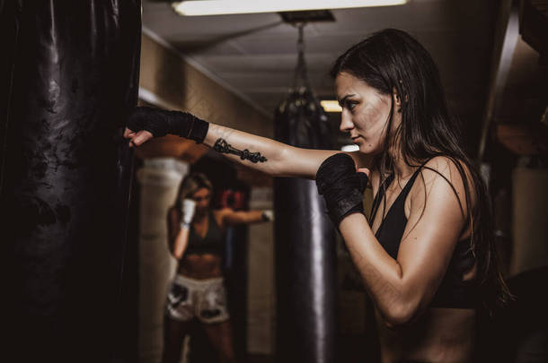 女子拳击手带皮袋训练的肖像