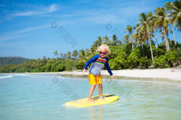 在亚洲热带海滩冲浪的小男孩。在海浪冲浪<strong>板</strong>上的孩子。为孩子们开展水上运动活动。孩子用身体<strong>板</strong>游泳。年轻的冲浪者在异国风情的大海。儿童游泳和眼穿