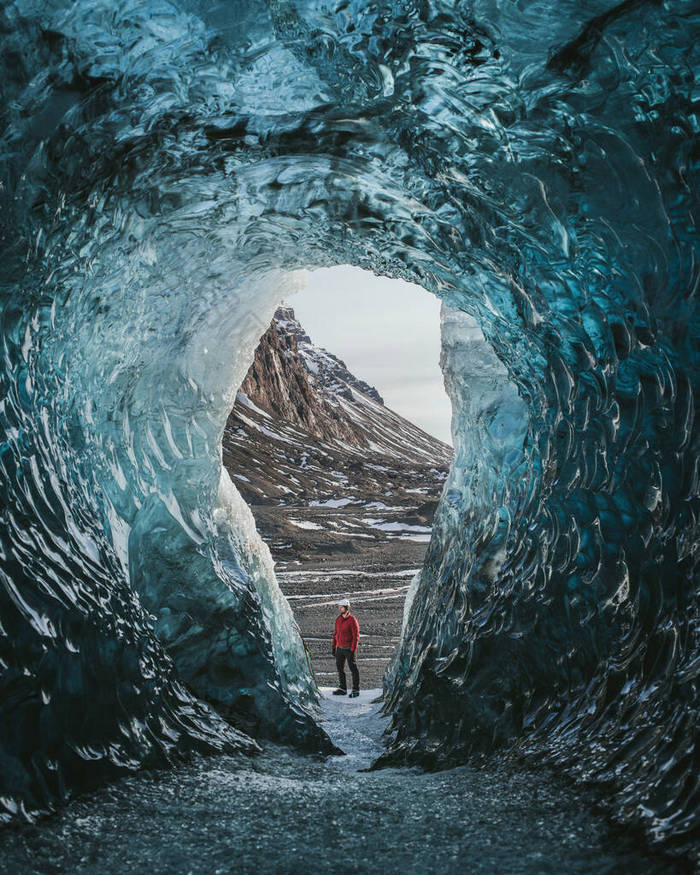 在冰洞里背着背包的旅行者。站在冰岛瓦特纳冰川上的人。史诗洛杉矶