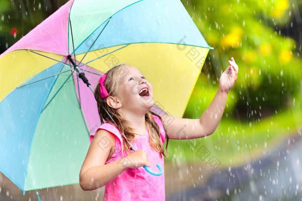 孩子在雨中玩耍。孩子们带着雨伞在外面下大雨.第一次春雨中被抓住的小女孩。秋天的雨天使孩子们在户外玩得很开心.在热带风暴中奔跑的儿童.