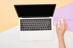 在米色、紫色和白色背景上使用笔记本电脑和电脑鼠标的裁剪视图